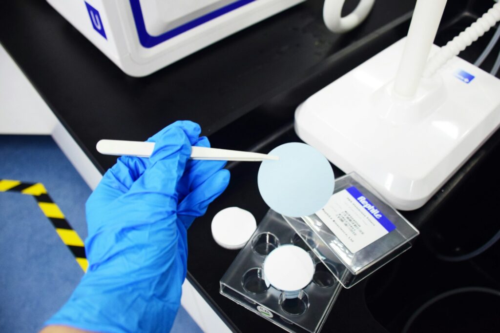 A scientist in a lab coat examining a large petri dish under blue light in a modern laboratory environment.