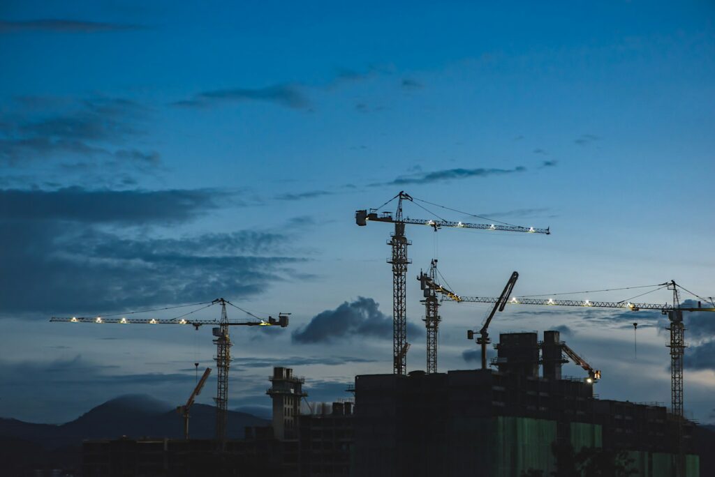 Construction cranes against a twilight sky, symbolising large-scale engineering and building projects.